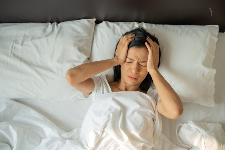 Unhappy exhausted mature woman with closed eyes lying in bed - how to improve sleep
